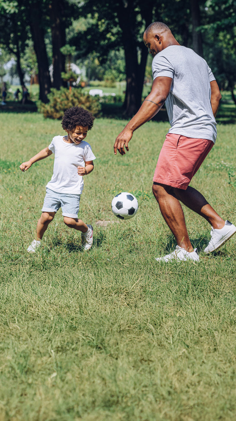 Man and child playing soccer in a park